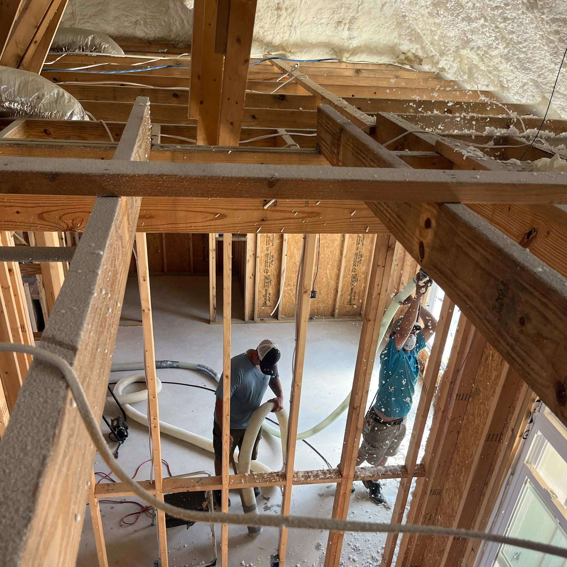 cellulose-insulation-installation-for-multifamily-new-construction Two workers installing cellulose insulation in a wooden-framed construction