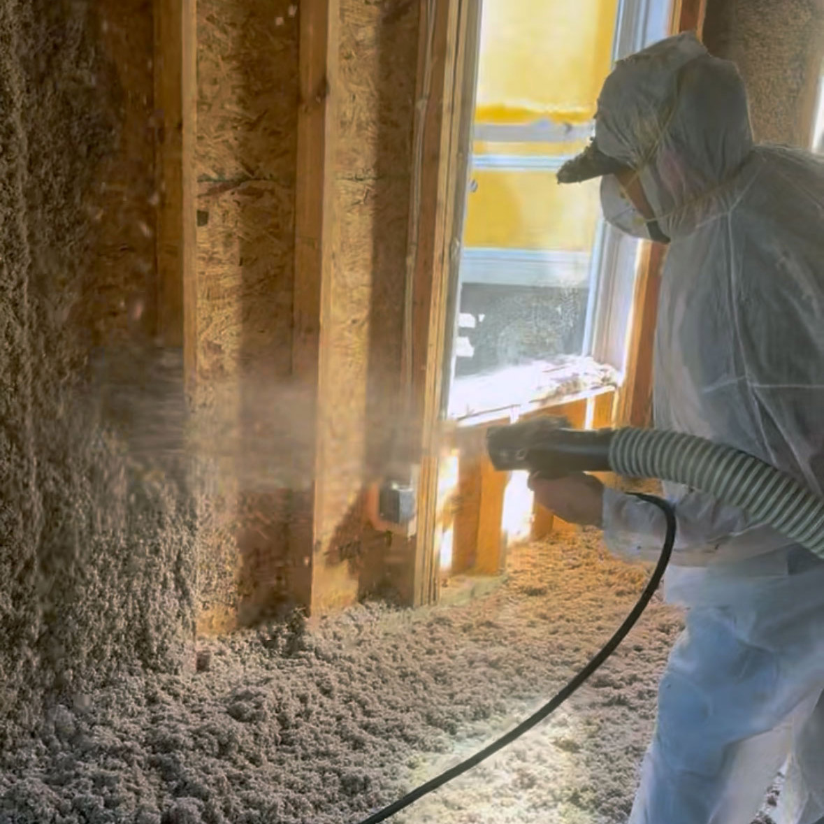 cellulose-insulation-installation-interior Worker in protective gear spraying cellulose insulation onto interior wall
