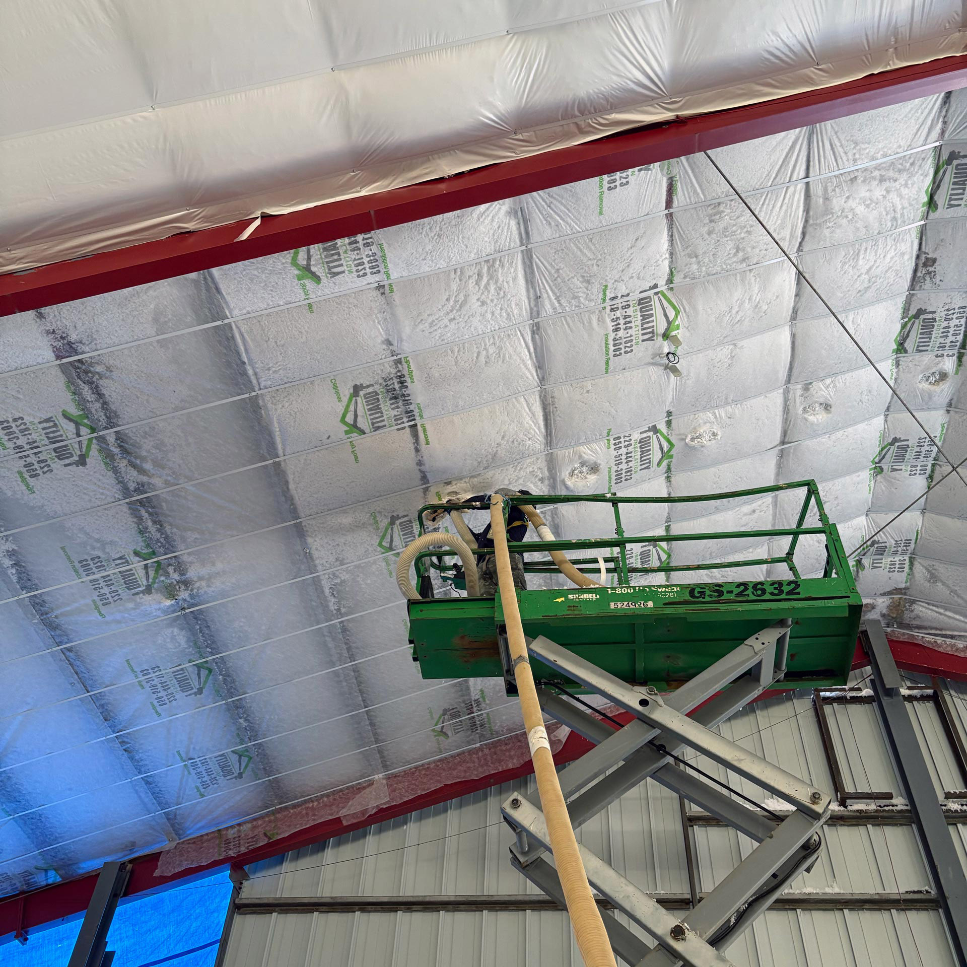 Worker in a lift installing insulation on a large ceiling