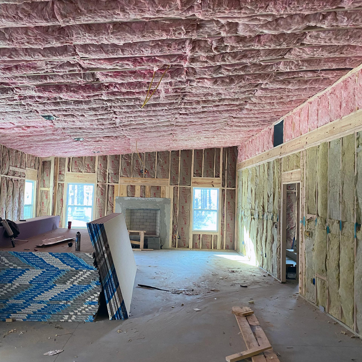 Fiberglass insulation covers ceiling and walls of an unfinished room