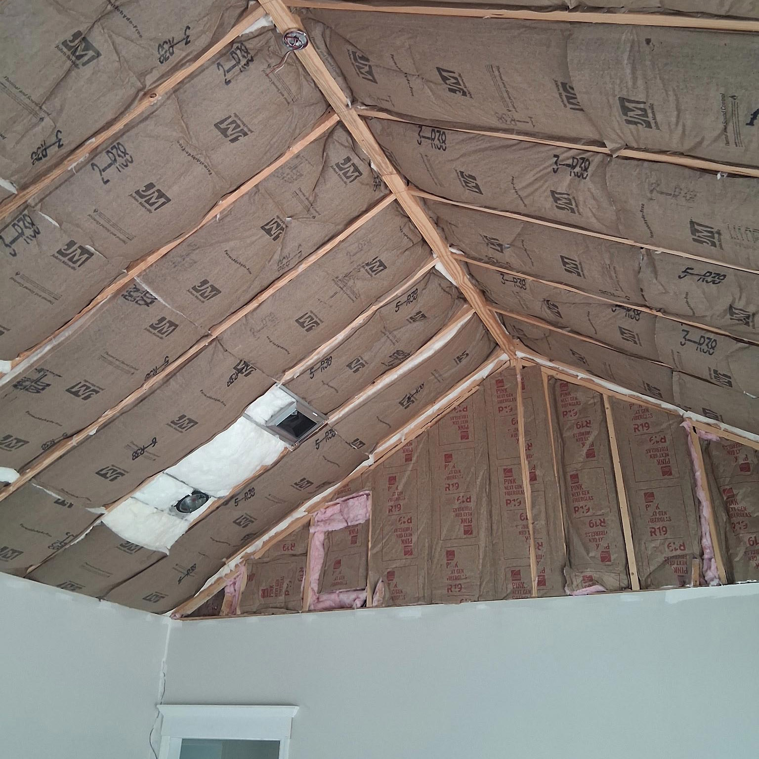 Fiberglass insulation installed in ceiling and walls of a room