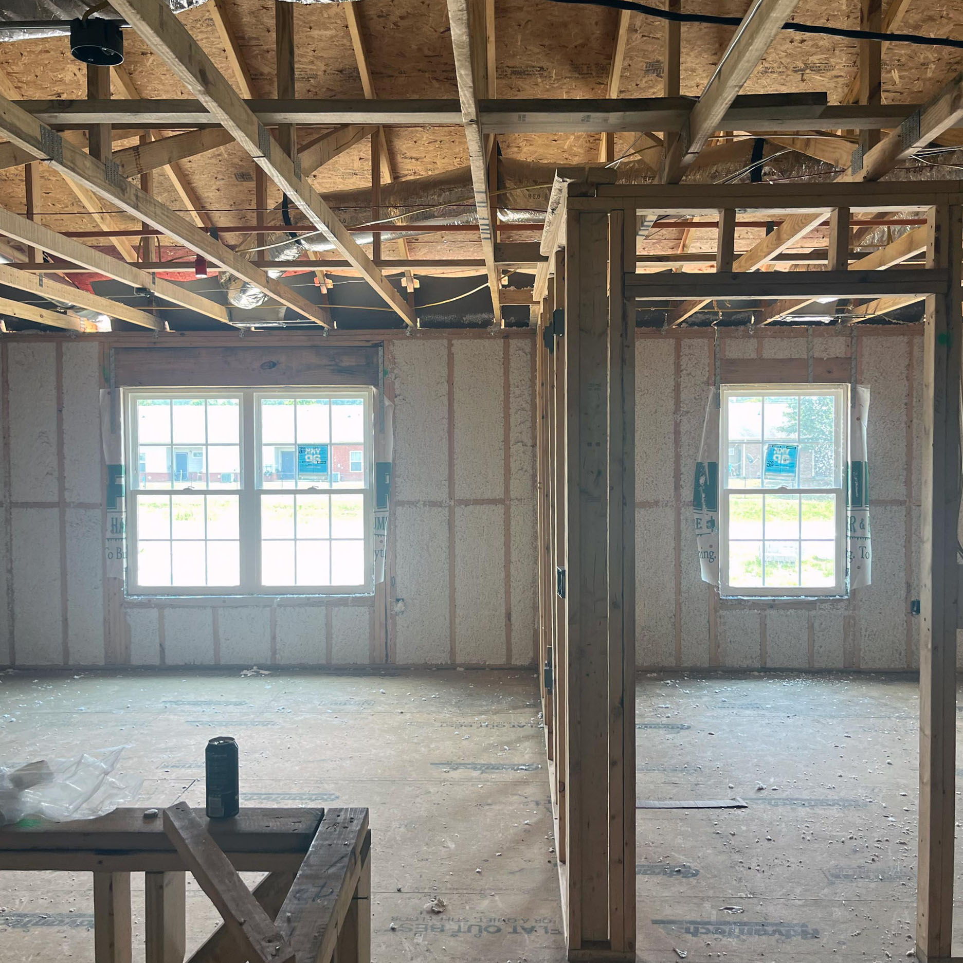 fiberglass-insulation Interior view of unfinished room with fiberglass insulation, exposed beams, and two windows