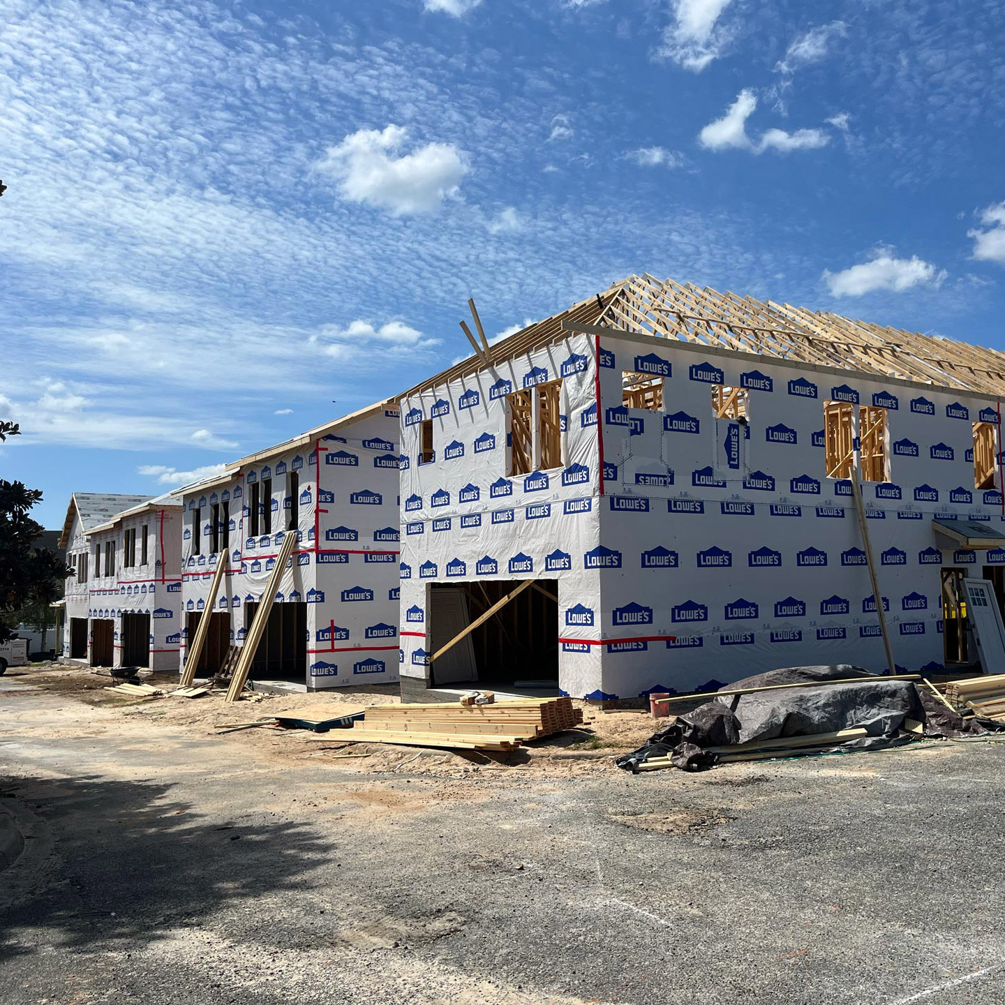 multifamily-insulation-installation Multifamily building under construction wrapped in Lowe's branded insulation material, clear sky above