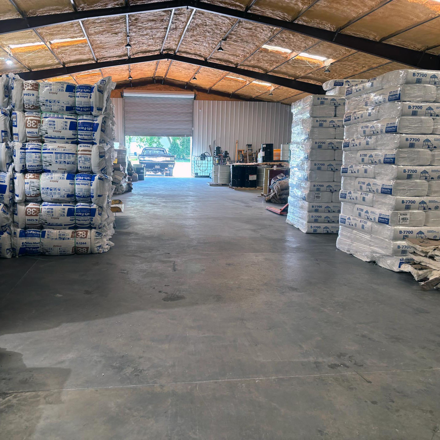 Stacks of insulation materials in a large warehouse with open garage door