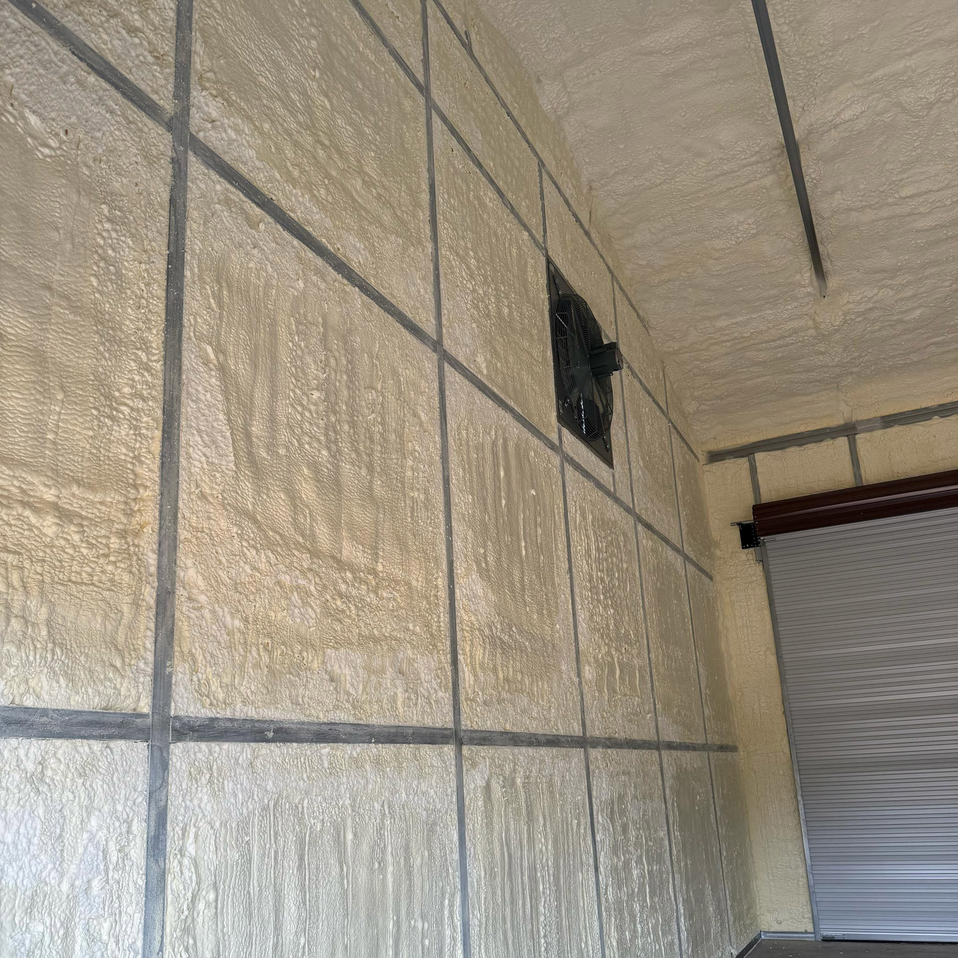 Spray foam insulation covering garage walls and ceiling with visible texture