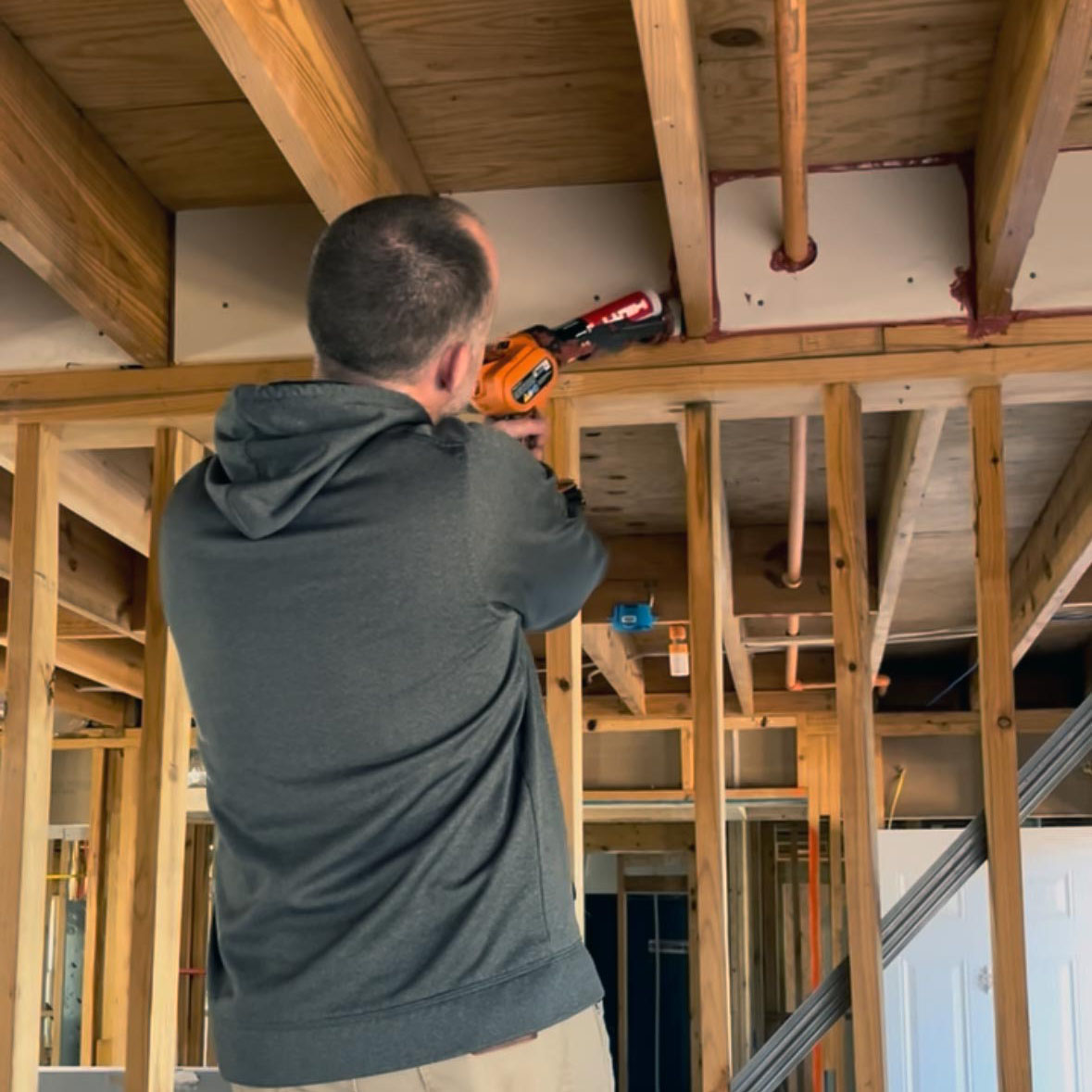 technicial-air-aealing-in-multifamily-new-construction Technician applying sealant in new construction framing with caulking gun