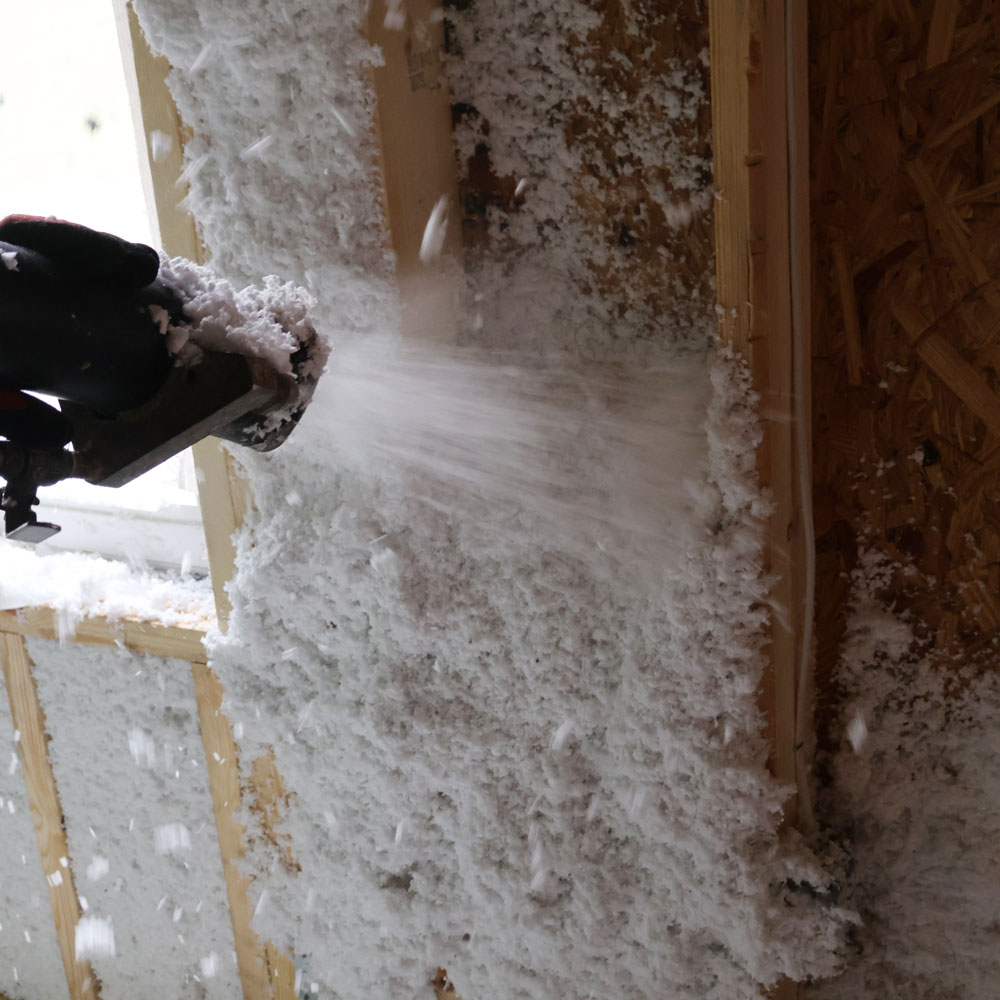 Spray foam insulation being applied to a wooden wall frame in a home construction site