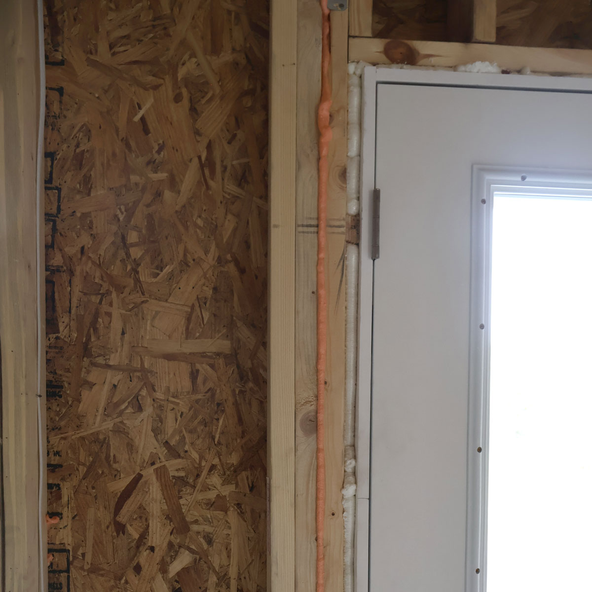 Air-sealed residential door with visible insulation foam on wooden frame