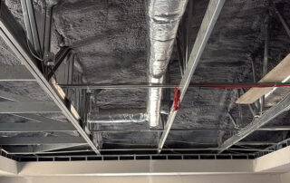 Open-cell spray foam insulation applied around HVAC ductwork in the ceiling of the Wakulla Library commercial project.