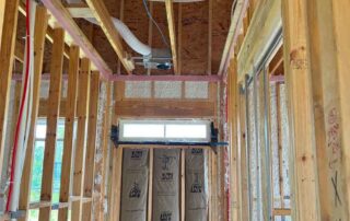 Quality Insulation of Valdosta installed kraft-faced fiberglass batts in a wall below a transom window and sprayed Johns Manville Spider Plus into the surrounding wall cavities, with Owens Corning Rim Seal along the top plates, in a new home.