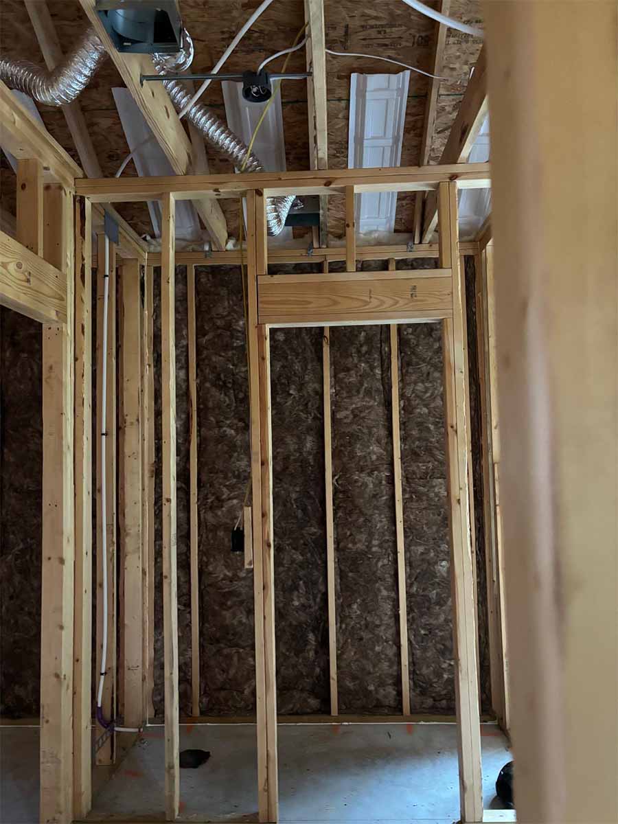 Quality Insulation of Valdosta installed fiberglass batts in wall cavities of a small room viewed through a framed doorway in Hahira, GA.
